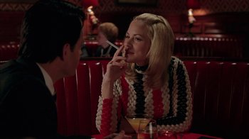 Movie still from “Auto Focus” (2002), directed by Paul Schrader – A man and a woman sitting at a table in front of a drink; Medium shot, Over the shoulder angle