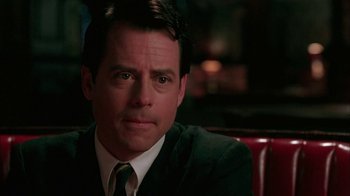 Movie still from “Auto Focus” (2002), directed by Paul Schrader – A man in a suit and tie sitting at a table; Close Up shot, Over the shoulder angle