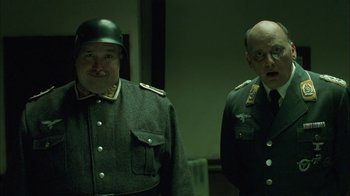 Movie still from “Auto Focus” (2002), directed by Paul Schrader – Two men dressed in military uniforms in a dark room; Medium shot, Low angle