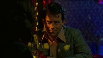 Movie still from “Auto Focus” (2002), directed by Paul Schrader – A man sitting at a table with a drink in front of him; Close Up shot, Over the shoulder angle