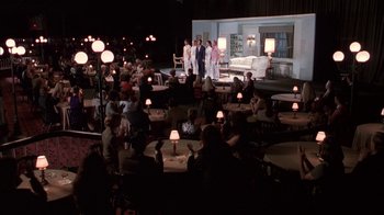 Movie still from “Auto Focus” (2002), directed by Paul Schrader – A group of people standing in a room with lamps; Extreme Wide shot, High angle