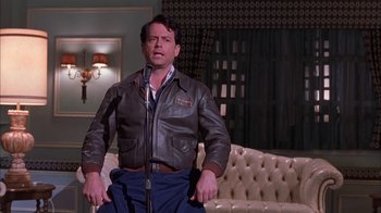 Movie still from “Auto Focus” (2002), directed by Paul Schrader – A man in a brown leather jacket is singing; Medium shot, Low angle
