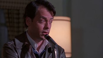 Movie still from “Auto Focus” (2002), directed by Paul Schrader – A man is speaking into a microphone in front of a lamp; Close Up shot, Low angle