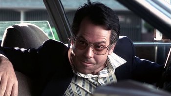 Movie still from “Auto Focus” (2002), directed by Paul Schrader – A man sitting in the back seat of a car wearing glasses; Close Up shot, Low angle