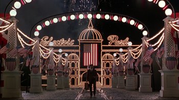 Movie still from “Avalon” (1990), directed by Barry Levinson – A man sitting in front of an electric park sign; Wide shot, High angle
