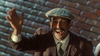 Movie still from “Avalon” (1990), directed by Barry Levinson – A man wearing a suit and a hat smiling for the camera; Close Up shot, Low angle