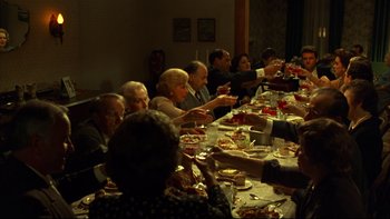 Movie still from “Avalon” (1990), directed by Barry Levinson – A group of people sitting at a dinner table eating food; Wide shot, High angle