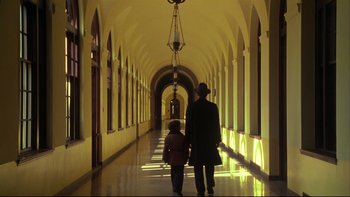 Movie still from “Avalon” (1990), directed by Barry Levinson – A man and a child walking down a long hallway; Wide shot, Low angle