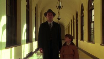 Movie still from “Avalon” (1990), directed by Barry Levinson – A man and a boy are walking down a hall way; Wide shot, Low angle