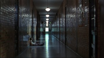 Movie still from “Avalon” (1990), directed by Barry Levinson – A person sitting on the ground in a hallway; Extreme Wide shot, High angle