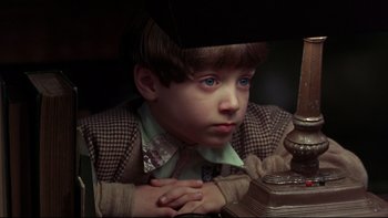 Movie still from “Avalon” (1990), directed by Barry Levinson – A young boy sitting in front of a lamp; Close Up shot, High angle