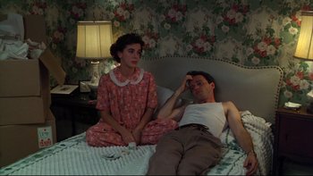 Movie still from “Avalon” (1990), directed by Barry Levinson – A man and a woman sitting on a bed in a room; Medium shot, High angle