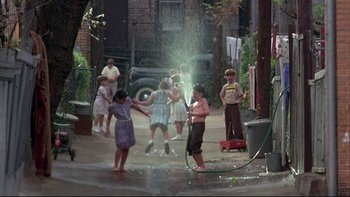 Movie still from “Avalon” (1990), directed by Barry Levinson – A group of children playing with a water hose in the street; Wide shot, High angle