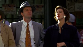 Movie still from “Avalon” (1990), directed by Barry Levinson – A man and a woman standing next to each other; Medium shot, Low angle