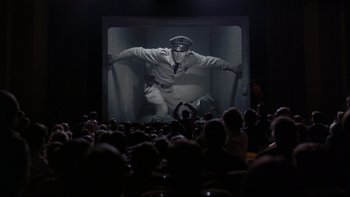 Movie still from “Avalon” (1990), directed by Barry Levinson – A crowd of people watching a movie on a big screen; Wide shot, Low angle