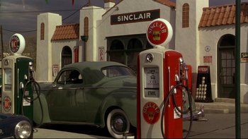 Movie still from “Avalon” (1990), directed by Barry Levinson – An old gas pump and a car in front of a gas station; Wide shot, Over the shoulder angle