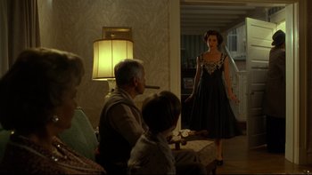 Movie still from “Avalon” (1990), directed by Barry Levinson – A woman in a black dress standing in a living room; Wide shot, Over the shoulder angle