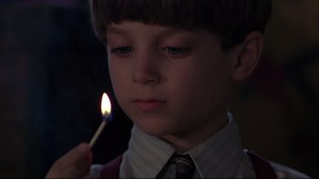 Movie still from “Avalon” (1990), directed by Barry Levinson – A young boy holding a lit match in his hand; Close Up shot, Low angle