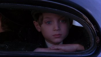 Movie still from “Avalon” (1990), directed by Barry Levinson – A young boy sitting in the back seat of a car; Close Up shot, High angle