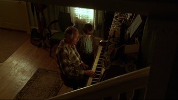 Movie still from “Avalon” (1990), directed by Barry Levinson – An older man and a young boy playing a piano; Medium shot, High angle