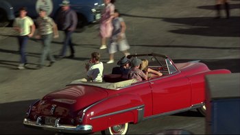 Movie still from “Avalon” (1990), directed by Barry Levinson – A group of people riding in the back of a red car; Wide shot, High angle