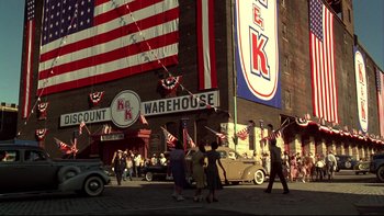 Movie still from “Avalon” (1990), directed by Barry Levinson – A group of people walking down a street under a large american flag; Extreme Wide shot, High angle