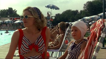 Movie still from “Avalon” (1990), directed by Barry Levinson – A woman and a child sitting on a beach chair; Medium shot, Over the shoulder angle