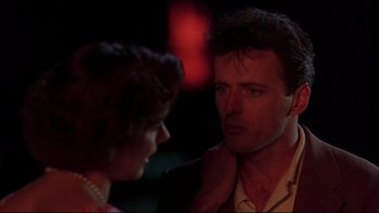 Movie still from “Avalon” (1990), directed by Barry Levinson – A man and a woman standing next to each other in the dark; Close Up shot, Over the shoulder angle