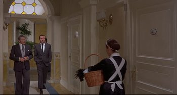 Movie still from “Avanti!” (1972), directed by Billy Wilder – A woman in a maid's outfit is carrying a basket; Wide shot, Low angle