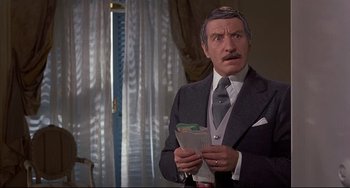 Movie still from “Avanti!” (1972), directed by Billy Wilder – A man in a suit and tie holding papers in his hands; Medium shot, Over the shoulder angle