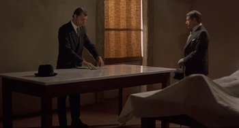 Movie still from “Avanti!” (1972), directed by Billy Wilder – A man sitting at a table in front of a window; Wide shot, High angle