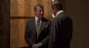 Movie still from “Avanti!” (1972), directed by Billy Wilder – Two men in suits talking to each other; Medium shot, Over the shoulder angle