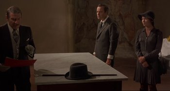 Movie still from “Avanti!” (1972), directed by Billy Wilder – A man standing in front of a table with a hat on it; Medium shot, High angle