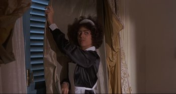 Movie still from “Avanti!” (1972), directed by Billy Wilder – A woman dressed as a french maid in front of a window; Medium shot, Low angle