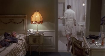 Movie still from “Avanti!” (1972), directed by Billy Wilder – A man in a white bathrobe walking out of a bathroom; Wide shot, High angle