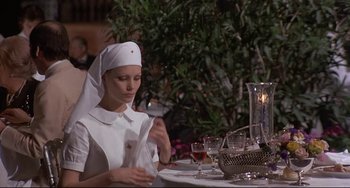 Movie still from “Avanti!” (1972), directed by Billy Wilder – A nun sitting at a table with a glass of red wine; Medium shot, Low angle