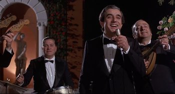 Movie still from “Avanti!” (1972), directed by Billy Wilder – A group of men in tuxedos singing into microphones; Medium shot, Low angle