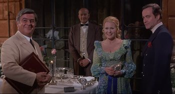 Movie still from “Avanti!” (1972), directed by Billy Wilder – A man and a woman standing in front of a table; Medium shot, Over the shoulder angle