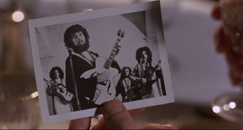 Movie still from “Avanti!” (1972), directed by Billy Wilder – A person holding a picture of a group of people playing guitar; Extreme Close Up shot, Low angle