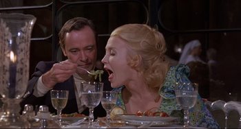 Movie still from “Avanti!” (1972), directed by Billy Wilder – A man and a woman sitting at a dinner table; Medium shot, High angle
