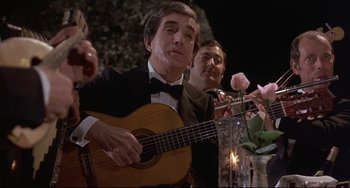 Movie still from “Avanti!” (1972), directed by Billy Wilder – A man in a tuxedo playing a guitar in front of other men; Medium shot, Low angle