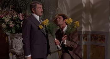 Movie still from “Avanti!” (1972), directed by Billy Wilder – Two men in suits and hats are holding flowers; Medium shot, Low angle