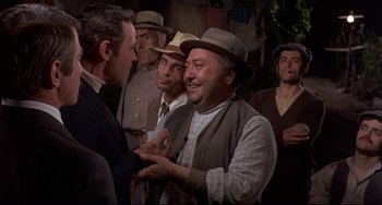 Movie still from “Avanti!” (1972), directed by Billy Wilder – A group of men standing next to each other in a room; Medium shot, Over the shoulder angle