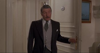 Movie still from “Avanti!” (1972), directed by Billy Wilder – A man in a suit and tie holding a bottle of beer; Medium shot, Over the shoulder angle