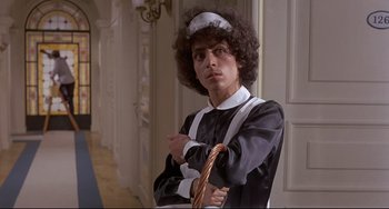 Movie still from “Avanti!” (1972), directed by Billy Wilder – A man in a maid's outfit posing for a picture; Medium shot, Low angle