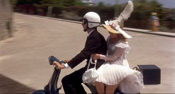 Movie still from “Avanti!” (1972), directed by Billy Wilder – A man and a woman riding a scooter on the street; Wide shot, High angle