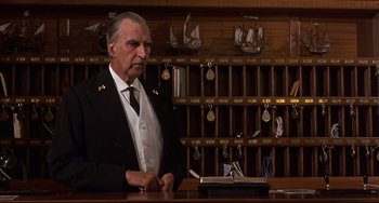 Movie still from “Avanti!” (1972), directed by Billy Wilder – An older man in a suit and tie standing in front of a desk; Medium shot, Low angle