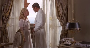 Movie still from “Avanti!” (1972), directed by Billy Wilder – A man and a woman standing next to each other in front of a window; Medium shot, Low angle