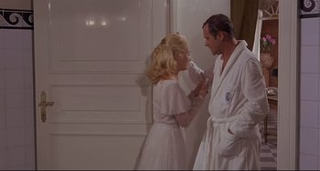 Movie still from “Avanti!” (1972), directed by Billy Wilder – A man and a woman standing next to each other; Medium shot, Over the shoulder angle