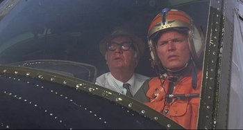 Movie still from “Avanti!” (1972), directed by Billy Wilder – A man and a man in a helmet looking at a plane; Close Up shot, Low angle